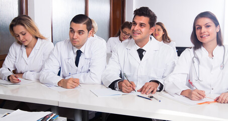 Fototapeta premium Students in white coats listen to lecture in audience