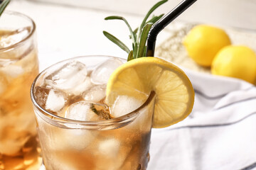 Glass of cold black tea with lemon on light background, closeup