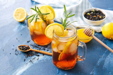 Mason jars of cold black tea with lemon on color background