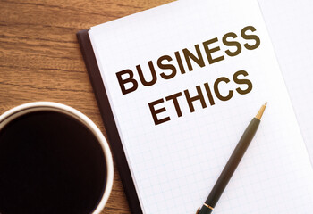BUSINESS ETHICS - text on notepad on wooden desk.