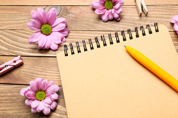 Empty notebook with flowers on wooden background