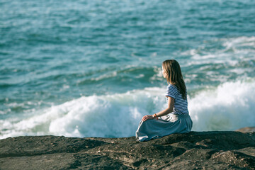 Yoga woman meditates in the lotus position on the ocean coast in at surf.