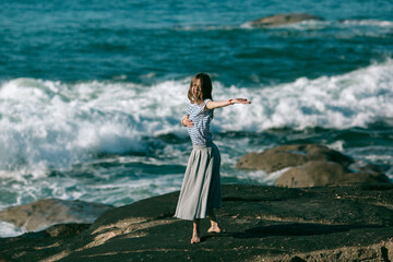 The dancer girl is engaged in dances on the ocean coast.