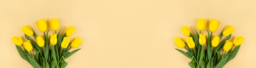 Bouquets of yellow tulips on beige background. Wide banner with copy space.