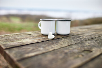 Enameled Two cups of tea in nature on wooden background, love, heart of marshmallow, travel...
