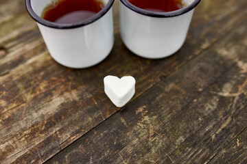 Enameled Two cups of tea in nature on wooden background, love, heart of marshmallow, travel concept, Lifestyle moment at nature, Valentine day, copy space, top view.