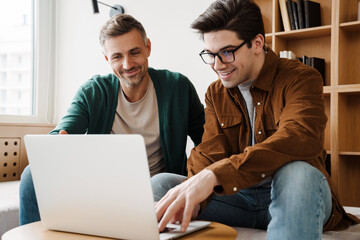 Happy young gay couple using laptop computer