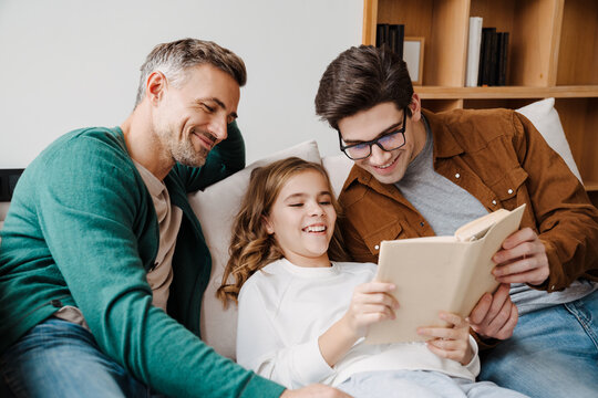 Happy gay parents reading book together