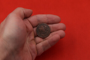Old copper coin of colonial India half anna in hand on red background