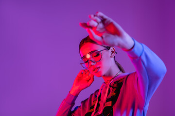 stylish woman in sunglasses with outstretched hand on blurred foreground isolated on purple