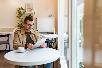 Handsome businessman reading newspaper in cafe