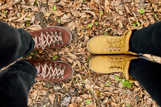 Modern young couple in hiking boots standing fallen autumn leaves in the forest, outdoor travel concept, top view, Love forever, valentine day..