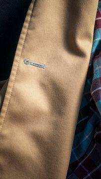 Ojal de bot&oacute;n con pespunte de hilo azul en gabardina beige