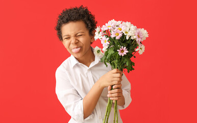 Funny African-American boy with bouquet of beautiful flowers on color background