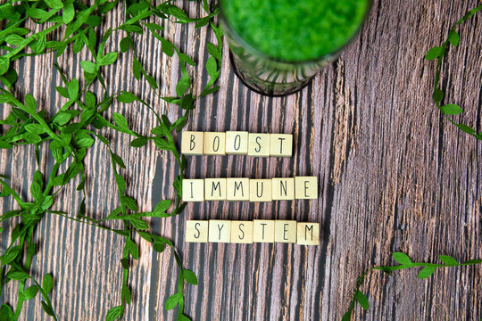 Boost Your Immune System - Inspirational Text On A Wooden Background Texture With A Glass Of Fresh Green, Vegetable Juice, Healthy Lifestyle And Wellbeing Concept