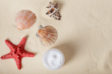 Fototapeta na wymiar Bottle of sunblock with shells on sand