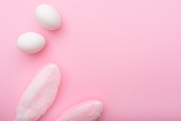 Fototapeta na wymiar White eggs and rabbit ears on pink background, Easter minimal flat lay, top view, space for text