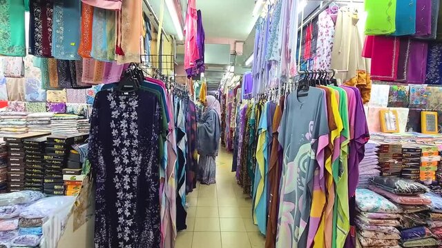 Woman Preparing Her Shop Selling Batik Corak Cloth And Garments - Tilt Down