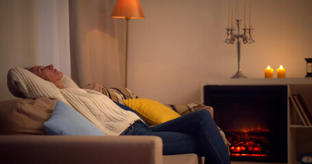 Side view of elegant senior lady relaxing on comfortable sofa at home