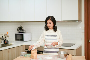 Mom prepares breakfast. A woman pours flour into a plate. The cooking process. Home kitchen