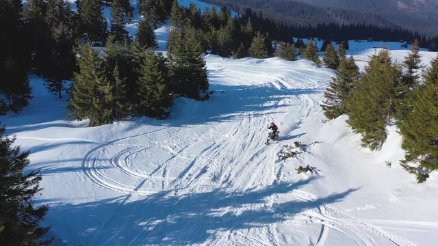 Snowbike riders in mountain valley in beautiful snow powder. Aerial video. Snowdirt bike with splashes and trail. Snowmobile winter sport riding