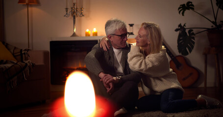 Retired mature couple sitting on floor together and relaxing in evening