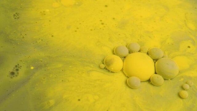 Grey and yellow acrylic paint bubbles move and explode in the milk 