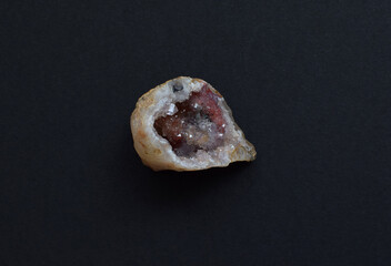 A beautiful geode with colored quartz crystals inside. Geological sample on a dark background.