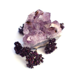 Beautiful druse of crystals of amethyst with dry herb of oregano on a white background. Magic...