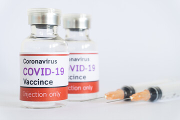 Bottles of vaccine COVID-19 virus with syringe on white background