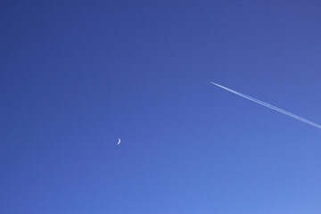 the young moon and airplane flying in the blue sky