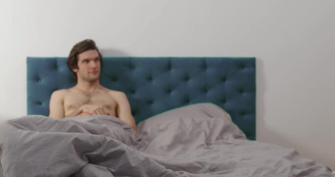 Attractive woman holding condom joining handsome man in bed
