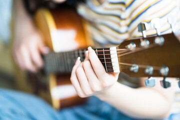 Fototapeta premium Young Asian girl is practicing guitar at home and composing music