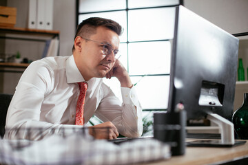 Young businessman using computer in his office. Handsome man working at his workplace.