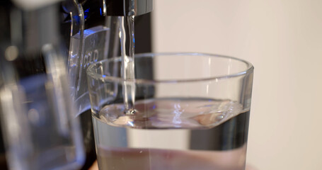 Close up of woman filling glass with modern water cooler