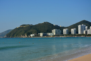 city view with green mountains near the blue sea under blue sky
