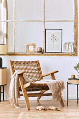 Modern composition of living room interior with design armchair, wooden shelf, old window, dried flowers in vase, brown mock up poster frame, decoration and elegant personal accessories. Template.