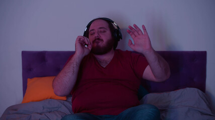 Obraz premium Relaxed man listening to music in wireless earphones lying in bed