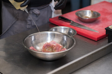 The chef in the restaurant marinates the chicken for the guests