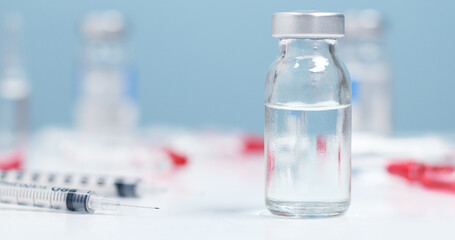 Medical bottle, vials, syringes injection for vaccination on blue background with copy space
