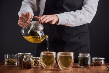 Barista pouring hot green tea into glass cups from a pot