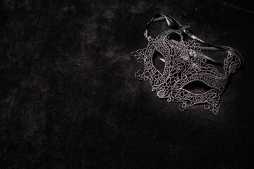 Venetian black woman mask, alone on a black surface,.