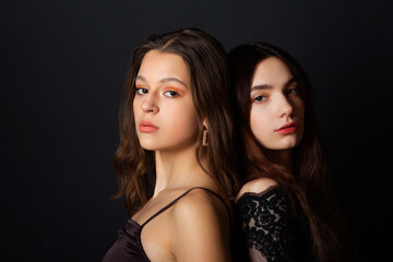 two beautiful young women with makeup and hairstyle on a black background 
