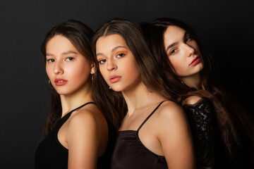 three beautiful young women with makeup and hairstyle on a black background 