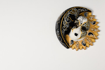 Venetian masks of white and black ceramic ornament with golden or gold highlights. White background.