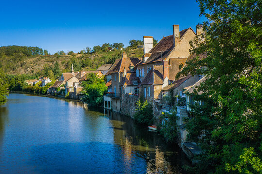 The riverbanks of the Aumance river, with view of the quaint medieval village of Herisson in Auvergne (France)