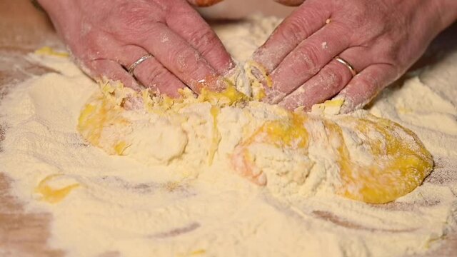(Selective focus) Slow motion video, overhead view of a woman making some Fettuccine, a homemade pasta from flour and fresh eggs. Ingredients for a dough such as pasta, bakery, cakes etc.