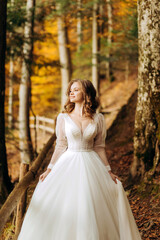 Amazing bride with wavy hair walks on a trail in autumn park.