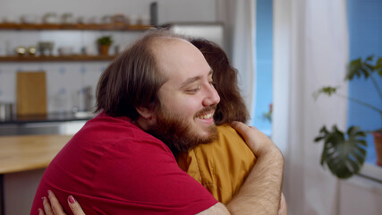 Loving elderly mother cuddling adult son and smiling at home together