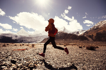 Woman trail runner cross country running in high altitude winter nature